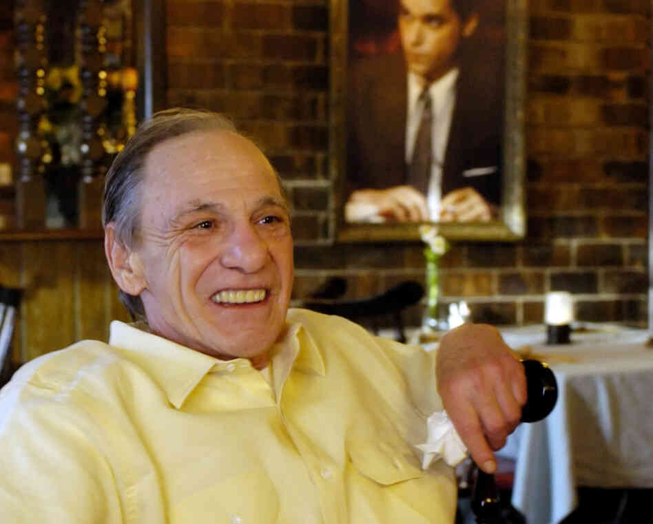 Henry Hill sits in the dining room of the Firefly restaurant in North Platte, Neb., in 2005. A portrait of actor Ray Liotta portraying Hill in the movie Goodfellas hangs on the wall behind him.