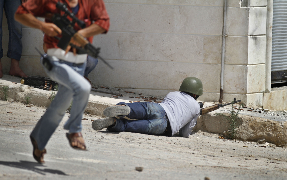 A Free Syrian Army fighter fires his weapon during clashes with Syrian troops near Idlib, Syria, on Friday. The U.N. said Saturday it is suspending its mission in Syria because of escalating violence.
