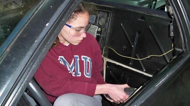 14-year-old Kathryn DiMaria drilling door rivets in her Pontiac Fiero.
