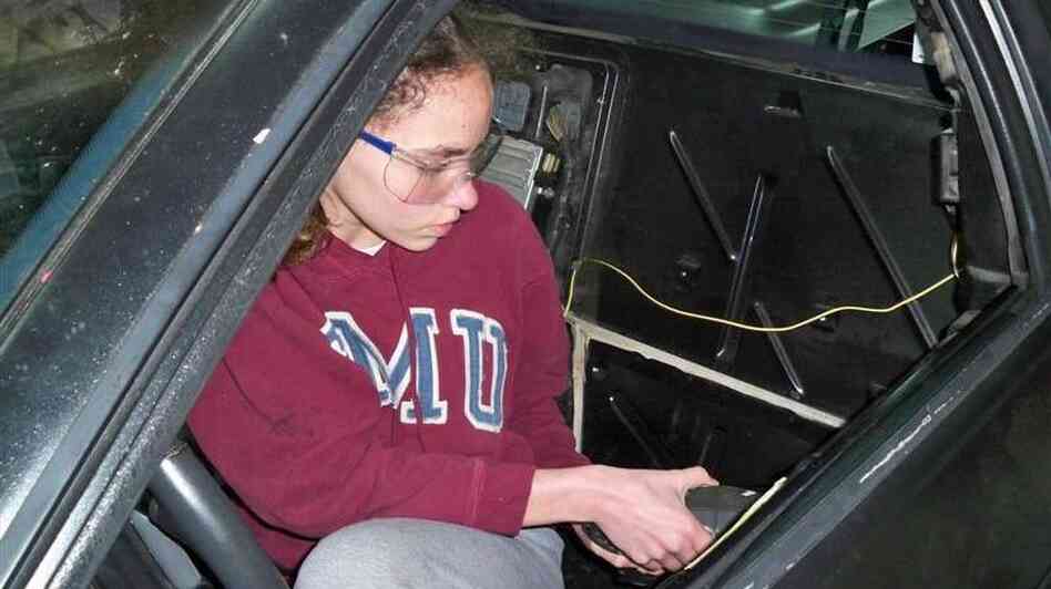 14-year-old Kathryn DiMaria drilling door rivets in her Pontiac Fiero.