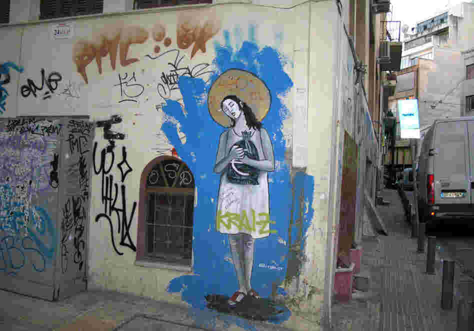 Graffiti in the rundown Athens neighborhood of Psiri depicts a woman clutching a sack of euros, a golden halo on her head and the title, "40 Years of Debt-ocracy." The street artist goes by the tag Bleeps.gr.