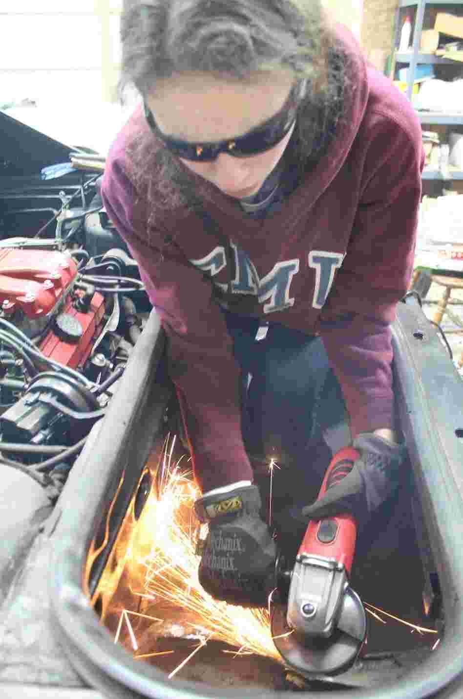 Kathryn DiMaria using her grinder to cut a hole in the trunk of her Pontiac Fiero. Kathryn DiMaria using her grinder to cut a hole in the trunk of her Pontiac Fiero.
