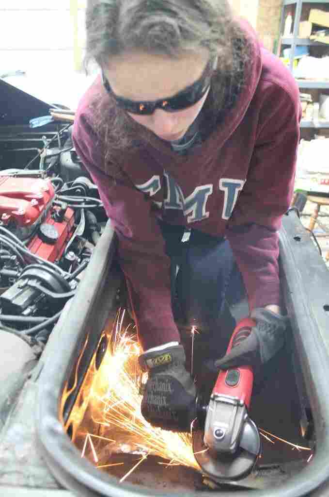 Kathryn DiMaria using her grinder to cut a hole in the trunk of her Pontiac Fiero. Kathryn DiMaria using her grinder to cut a hole in the trunk of her Pontiac Fiero.