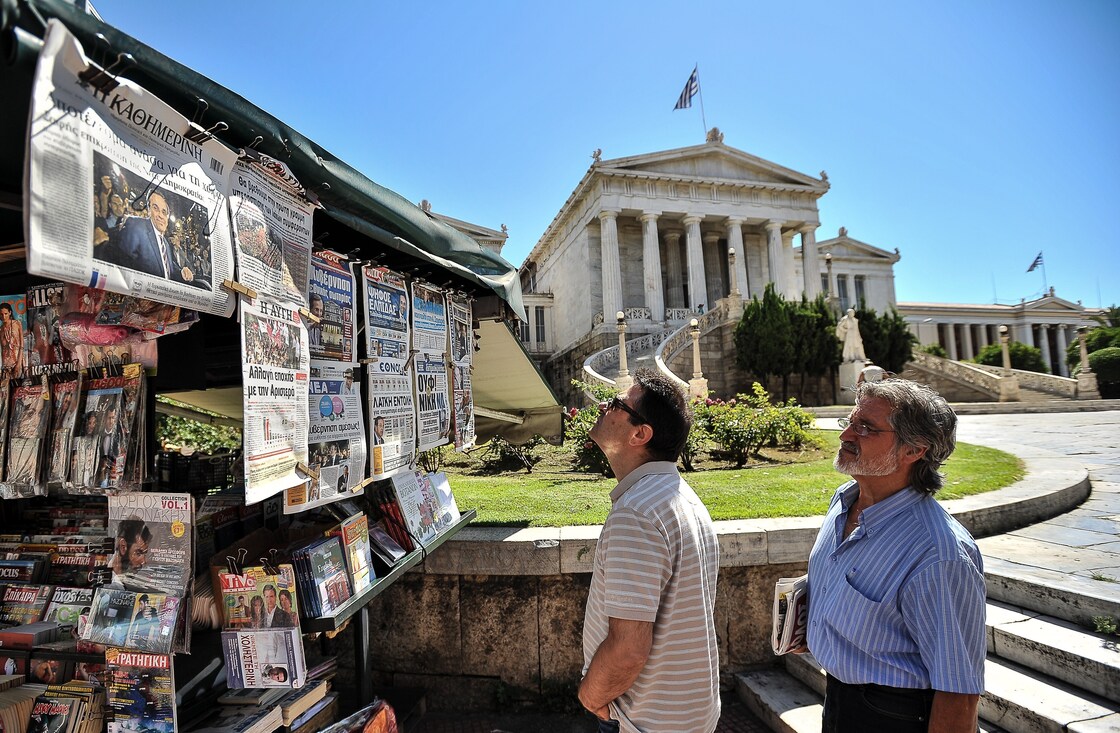 Two men read newspaper headlines in Athens on Monday as conservative Greek lawmakers raced to form a government a day after parliamentary elections.