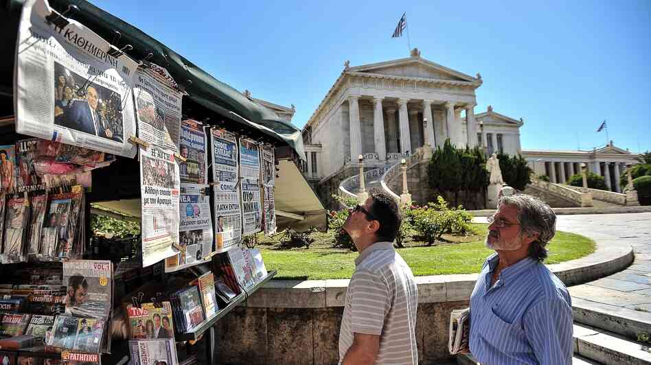 Two men read newspaper headlines in Athens on Monday as conservative Greek lawmakers raced to form a government a day after parliamentary elections.