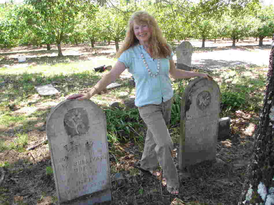 Jean McNear Powers stands between the twin headstones for her great-, great-, great-grandparents — pioneer couple Isaac and Polly Sullivan.
