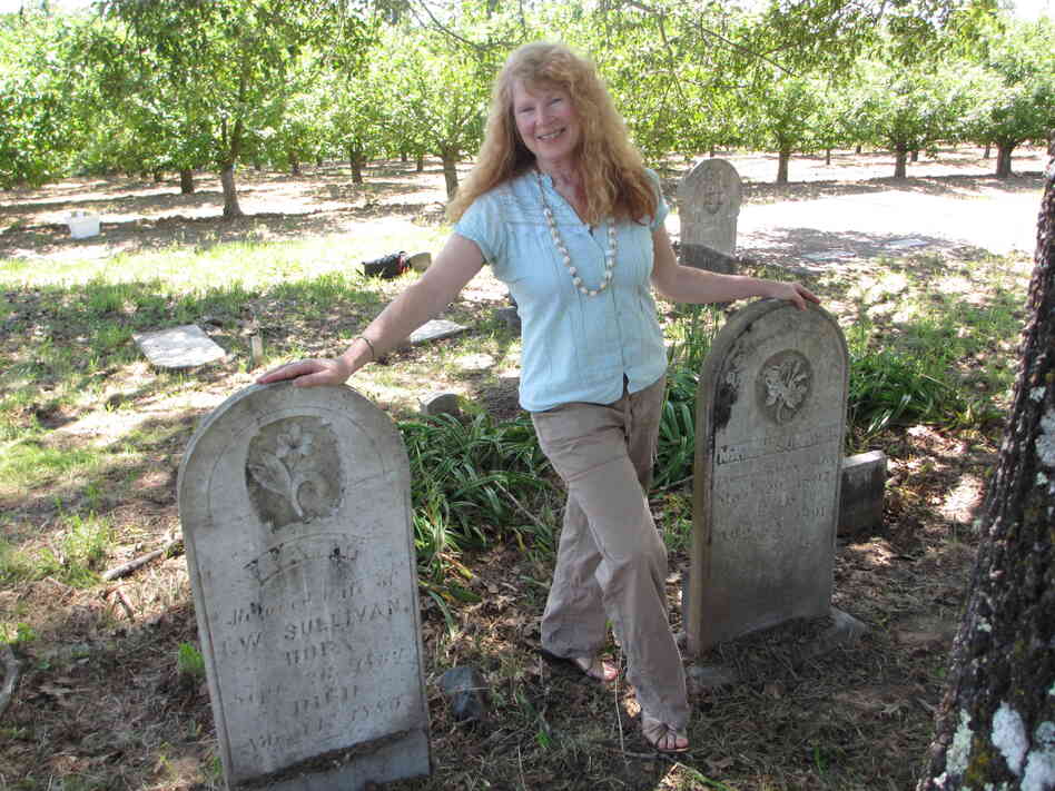 Jean McNear Powers stands between the twin headstones for her great-, great-, great-grandparents — pioneer couple Isaac and Polly Sullivan.