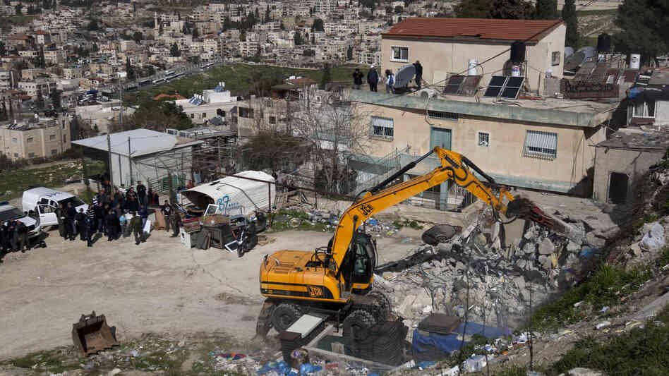 Israeli soldiers keep watch as a bulldozer demolishes a house belonging to a Palestinian resident in east Jerusalem on Feb. 13. Israel said the home was built without a permit.