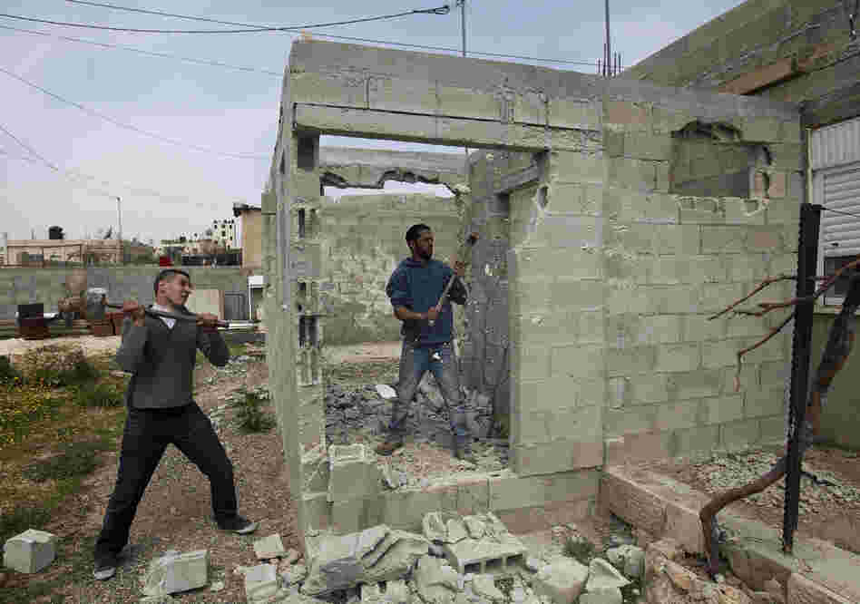 Palestinian Motasem Farrah (center) and a friend tear down Farrah's home in an Arab neighborhood in east Jerusalem, March 12. Israel often tells Palestinians who build without permits that they must tear down the house themselves or they will be charged by Israel for the cost of knocking it down.