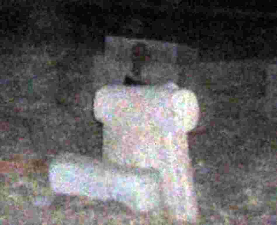A photo provided by Henry Flores shows a headstone with what some believe is a ghost in the frame, perched behind the tomb.