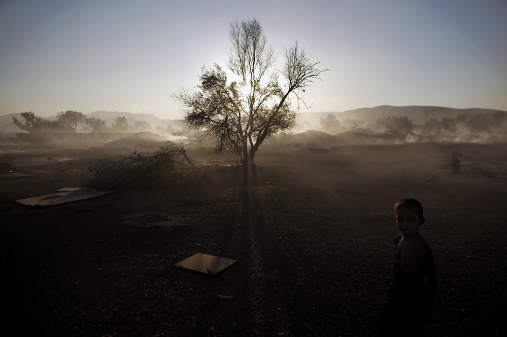 A Roma boy stands at a burnt Roma encampment, where the fire broke out in the industrial zone of Athens on Wednesday.