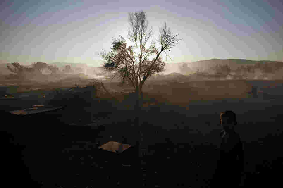 A Roma boy stands at a burnt Roma encampment, where the fire broke out in the industrial zone of Athens on Wednesday.