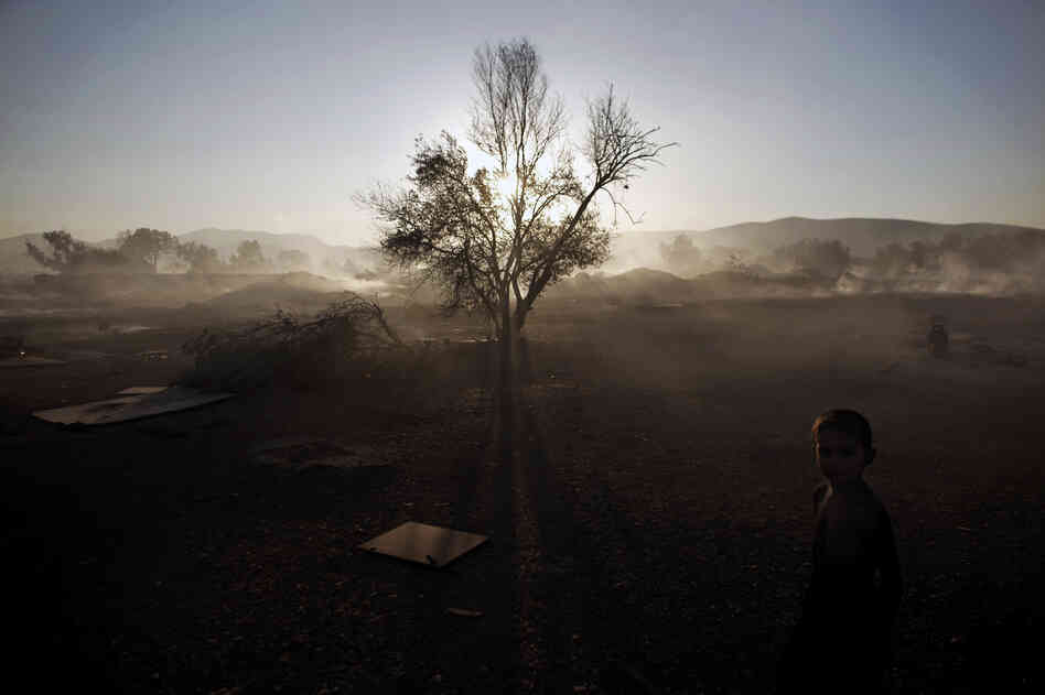 A Roma boy stands at a burnt Roma encampment, where the fire broke out in the industrial zone of Athens on Wednesday.