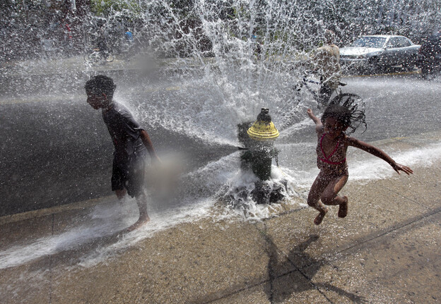 Four-year-old Solaris Arias, of Providence, R.I., right, jumps through water spraying from an open fire hydrant on Wednesday.