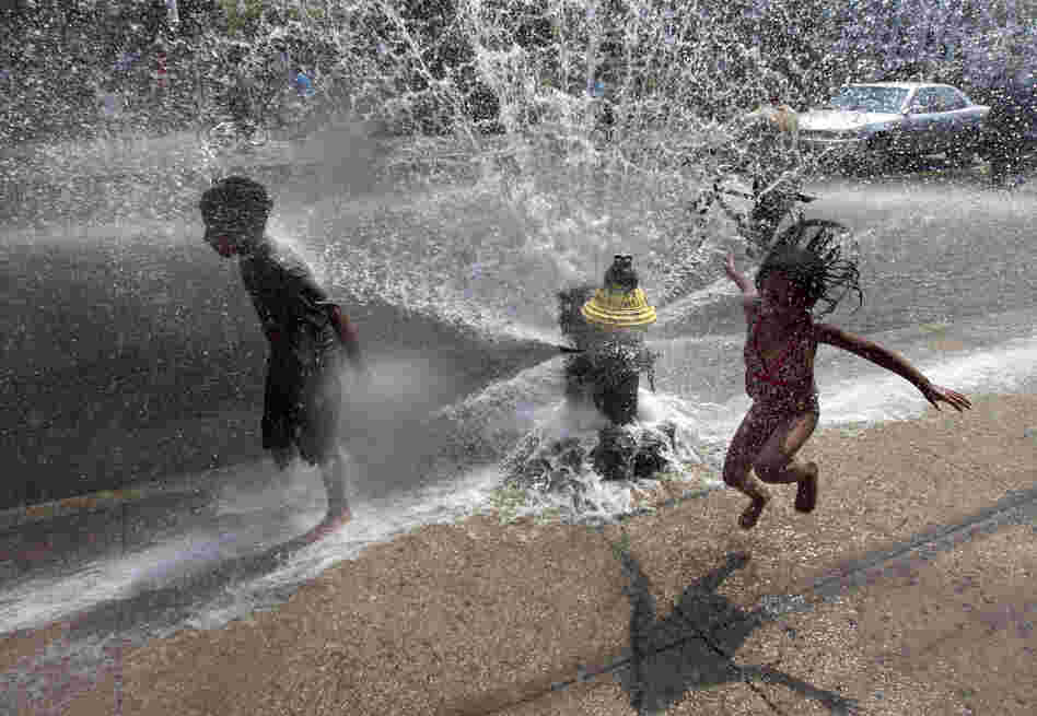 Four-year-old Solaris Arias, of Providence, R.I., right, jumps through water spraying from an open fire hydrant on Wednesday.