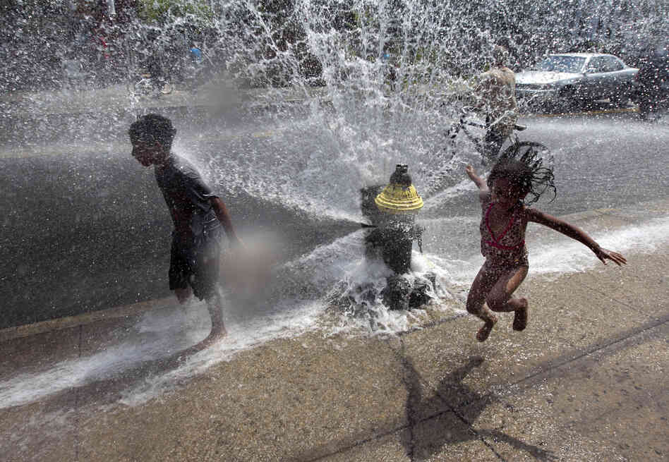 Four-year-old Solaris Arias, of Providence, R.I., right, jumps through water spraying from an open fire hydrant on Wednesday.