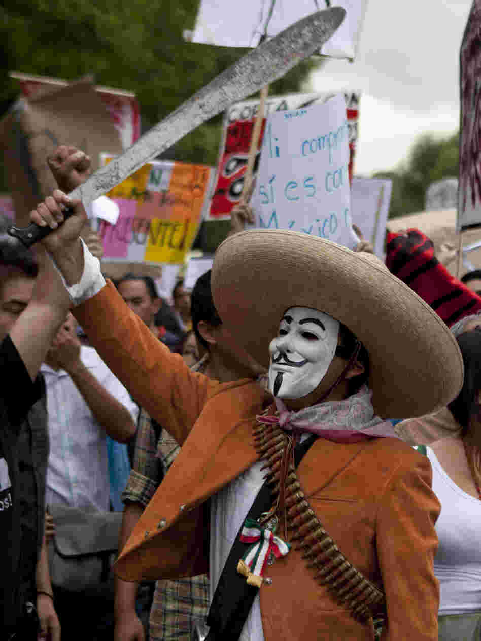 A man wearing a mask holds up a machete during a protest in May against a possible return of the old ruling Institutional Revolutionary Party in Mexico City.