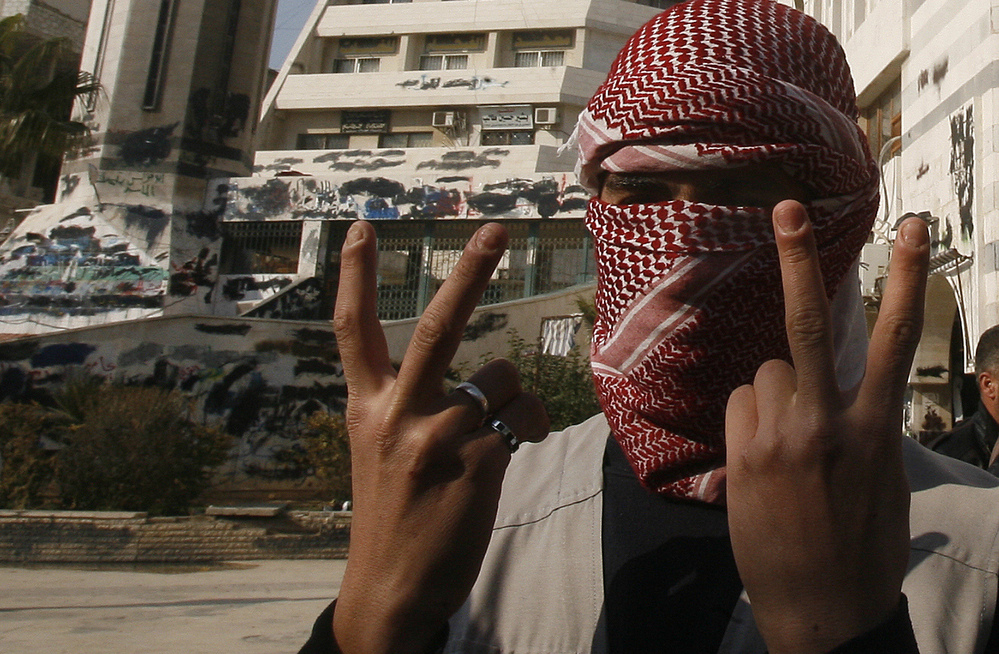 A Syrian youth flashes the victory sign as he stands in front of a building that was covered with anti-government graffiti — though local authorities painted over it — in the town of Duma, outside Damascus, in February.