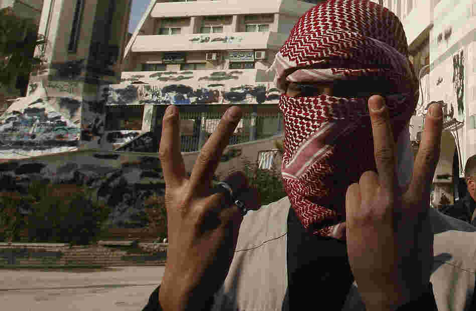 A Syrian youth flashes the victory sign as he stands in front of a building that was covered with anti-government graffiti — though local authorities painted over it — in the town of Duma, outside Damascus, in February.