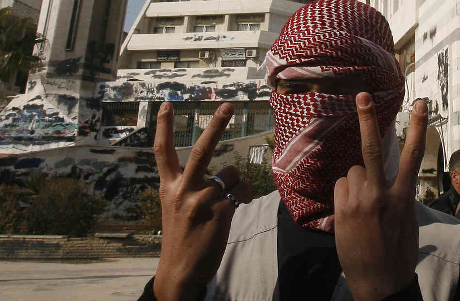 A Syrian youth flashes the victory sign as he stands in front of a building that was covered with anti-government graffiti — though local authorities painted over it — in the town of Duma, outside Damascus, in February.