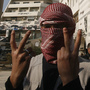 A Syrian youth flashes the victory sign as he stands in front of a building that was covered with anti-government graffiti — though local authorities painted over it — in the town of Duma, outside Damascus, in February. A Syrian youth flashes the victory sign as he stands in front of a building that was covered with anti-government graffiti — though local authorities painted over it — in the town of Duma, outside Damascus, in February.
