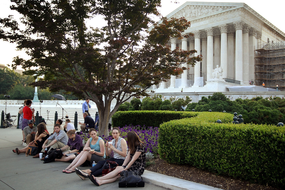 People wait outside the Supreme Court last week for word on the fate of the federal health overhaul law.