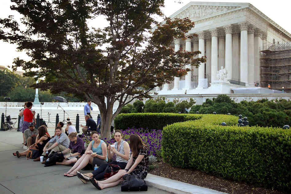 People wait outside the Supreme Court last week for word on the fate of the federal health overhaul law.