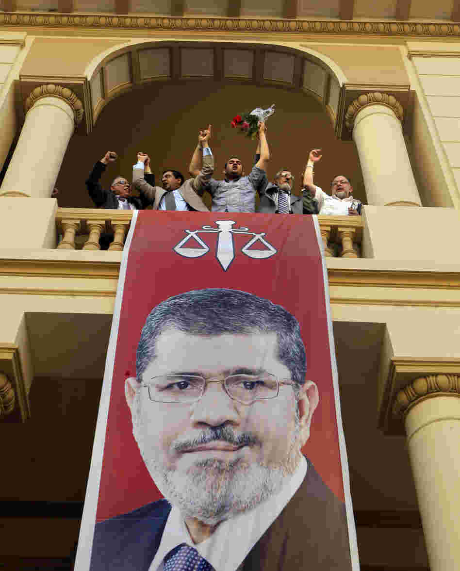 Egyptian campaign officials of the Muslim Brotherhood's candidate, Mohammed Morsi, celebrate over a giant poster of him at his campaign headquarters in Cairo, Egypt, Sunday.