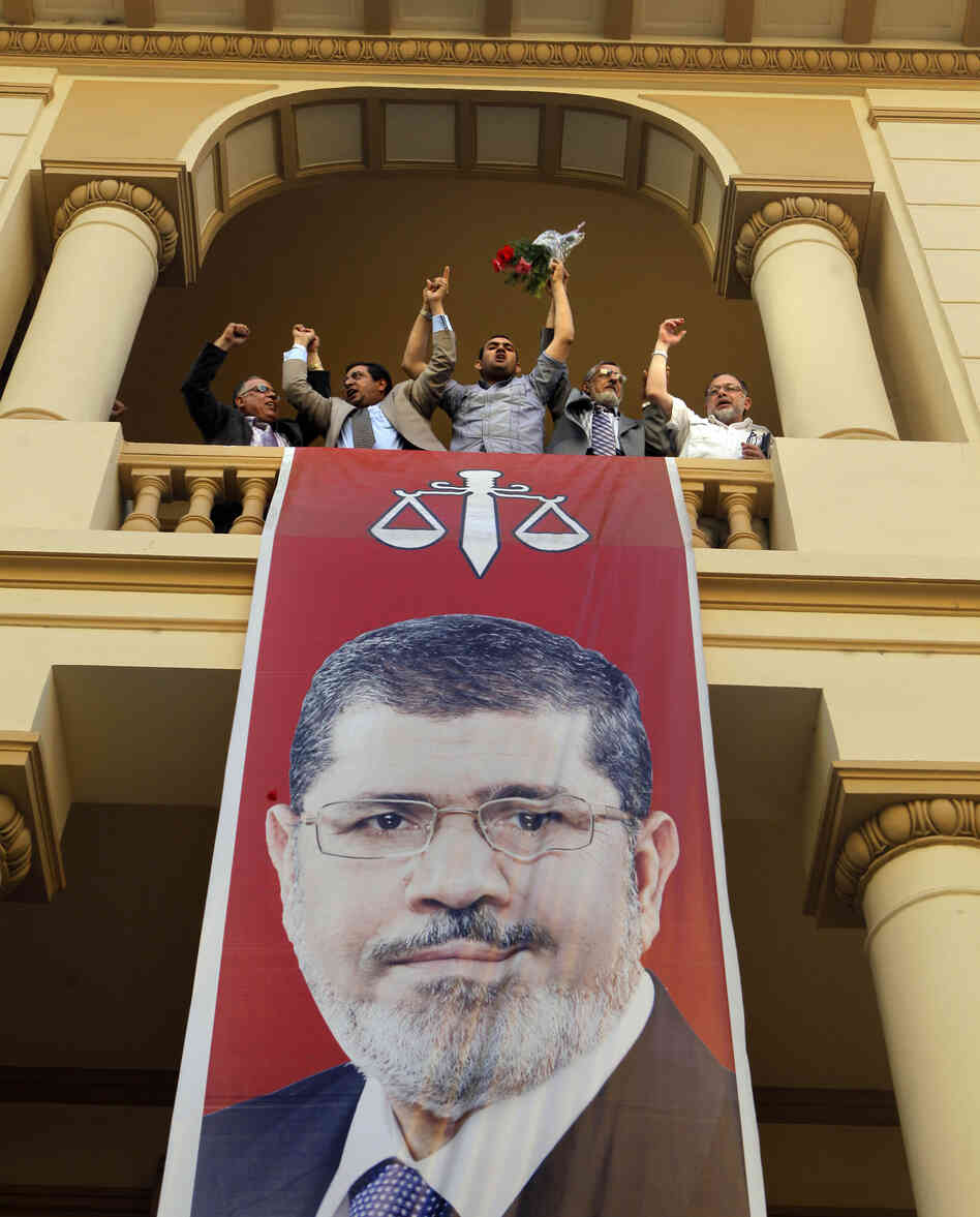 Egyptian campaign officials of the Muslim Brotherhood's candidate, Mohammed Morsi, celebrate over a giant poster of him at his campaign headquarters in Cairo, Egypt, Sunday.