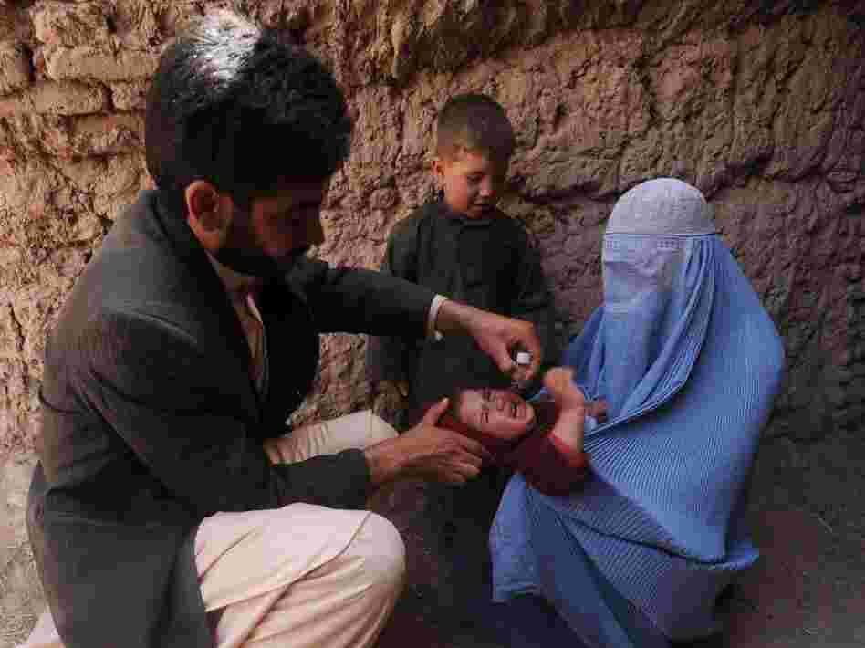 Many Afghan government programs depend on foreign aid. Here, an Afghan health worker administers a polio vaccine to a child in the western province of Herat on March 27.