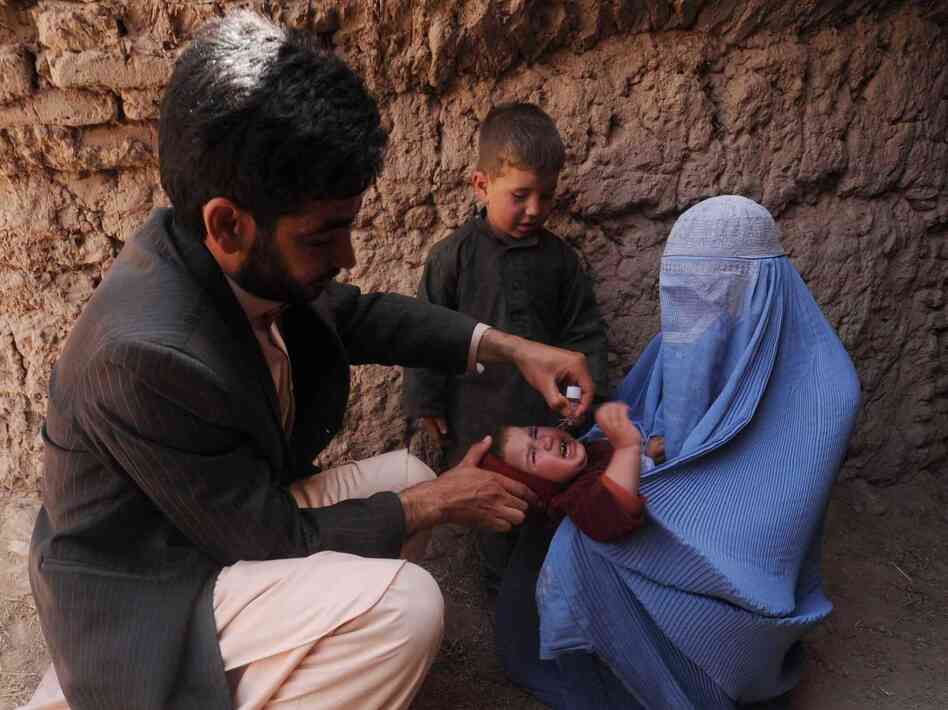 Many Afghan government programs depend on foreign aid. Here, an Afghan health worker administers a polio vaccine to a child in the western province of Herat on March 27.