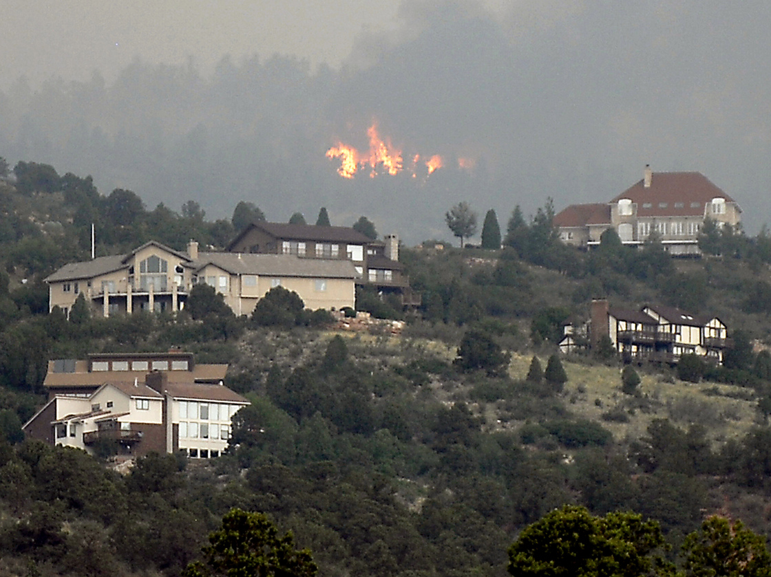 A wildfire burns near houses outside Colorado Springs, Colo., Sunday, when the fire grew to more than three square miles. More than 11,000 residents have been evacuated.