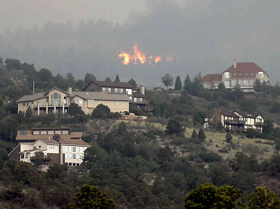 A wildfire burns near houses outside Colorado Springs, Colo., Sunday, when the fire grew to more than three square miles. More than 11,000 residents have been evacuated.