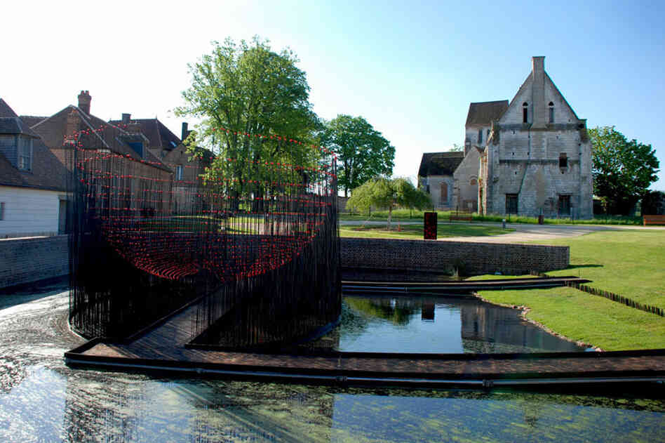 Andy Cao and Xavier Perrot's Red Bowl installation in Beauvais, France, allows visitors to cross a pond into a hemisphere of metal rods topped with red marbles.