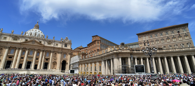 People gather on St. Peter's square to hear Pope Benedict XVI at the Vatican Sunday. The Vatican has hired Fox News correspondent Greg Burke to advise its press office.