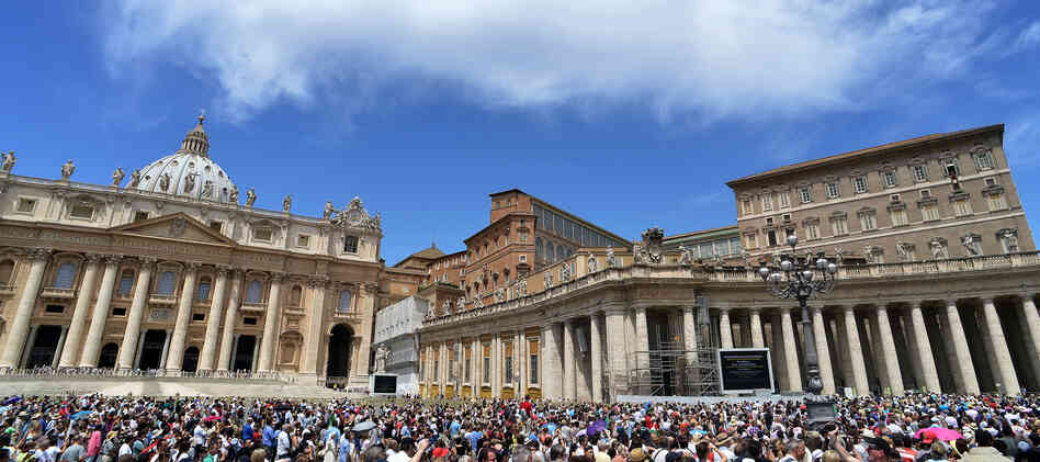 People gather on St. Peter's square to hear Pope Benedict XVI at the Vatican Sunday. The Vatican has hired Fox News correspondent Greg Burke to advise its press office.