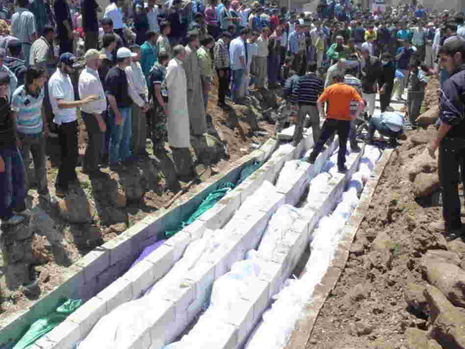May 26, 2012: In this picture provided by the Syrian opposition's Shaam News Network, people watch the mass burial of victims in Houla.