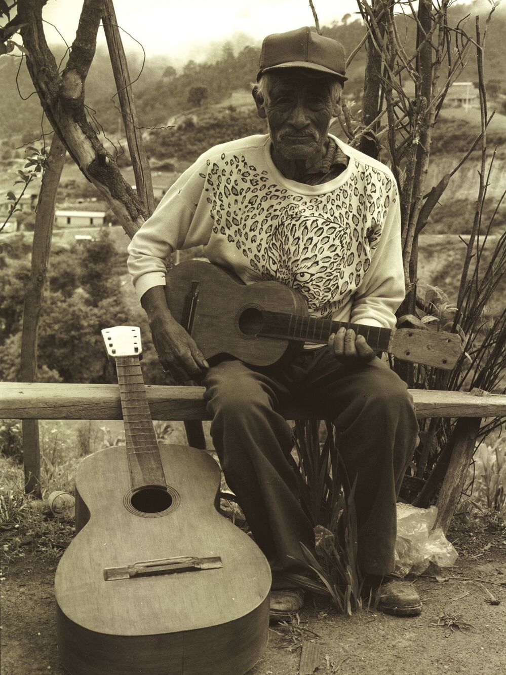 Don Telesforo next to a bajo quinto, holding a jarana mixteca.