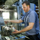 Brian Gasiewski removes the external housing for an industrial shock absorber from a CNC, or computer numerical control, machine at Fitzpatrick Manufacturing Co. in Sterling Heights, Mich.