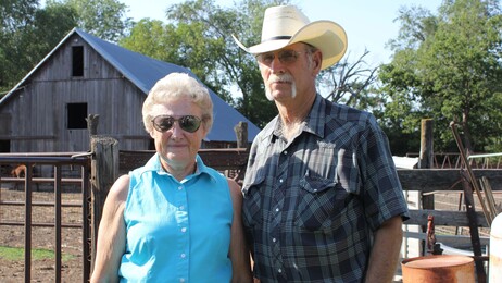 Barbara and Norman Roux stand in front of cattle pens on their farm outside of Moundridge, Kan., where she has raised cattle for nearly 70 years.