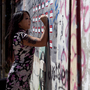 Candy Chang, co-founder of the website Neighborland, writes on an art installation in New Orleans in April. As part of a public street art project that later became Neighborland, Chang put nametag-like stickers on empty New Orleans storefronts for residents to write ideas for improving the city.