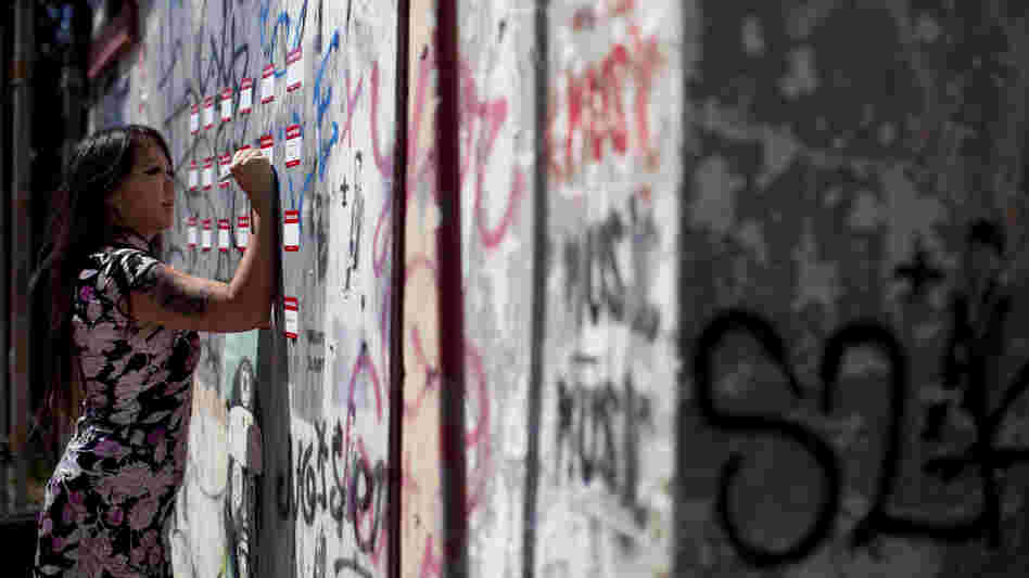 Candy Chang, co-founder of the website Neighborland, writes on an art installation in New Orleans in April. As part of a public street art project that later became Neighborland, Chang put nametag-like stickers on empty New Orleans storefronts for residents to write ideas for improving the city.