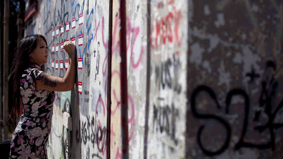 Candy Chang, co-founder of the website Neighborland, writes on an art installation in New Orleans in April. As part of a public street art project that later became Neighborland, Chang put nametag-like stickers on empty New Orleans storefronts for residents to write ideas for improving the city.