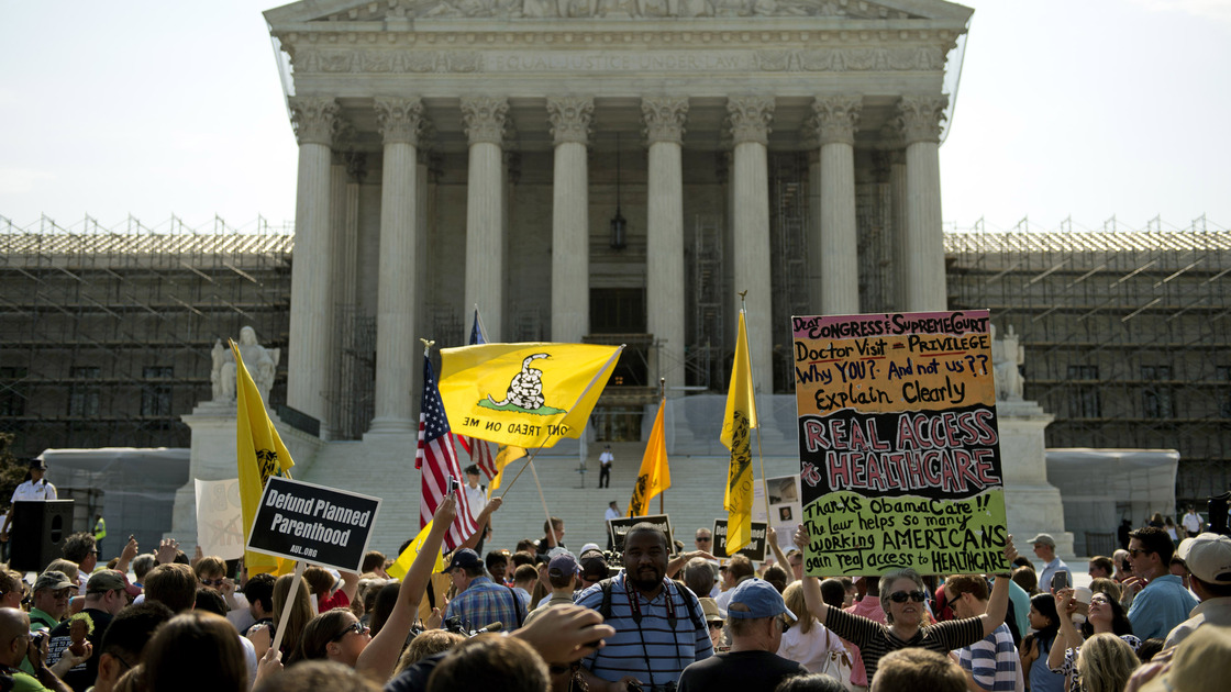 Protesters and supporters of President Obama's health care law await the Supreme Court's ruling Thursday. The court ruled to uphold the law. The focus now shifts to the states, which are responsible for the lion's share of getting people without insurance covered.