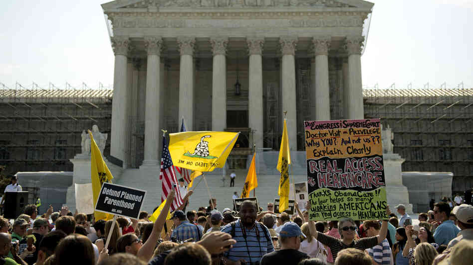 Protesters and supporters of President Obama's health care law await the Supreme Court's ruling Thursday. The court ruled to uphold the law. The focus now shifts to the states, which are responsible for the lion's share of getting people without insurance covered.