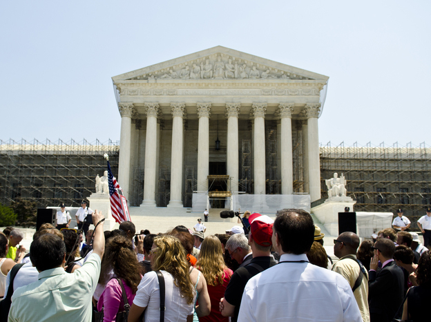 Protesters stand outside the U.S. Supreme Court on Thursday. The court's ruling upholding the federal health care law is expected to have wide-reaching implications for businesses.