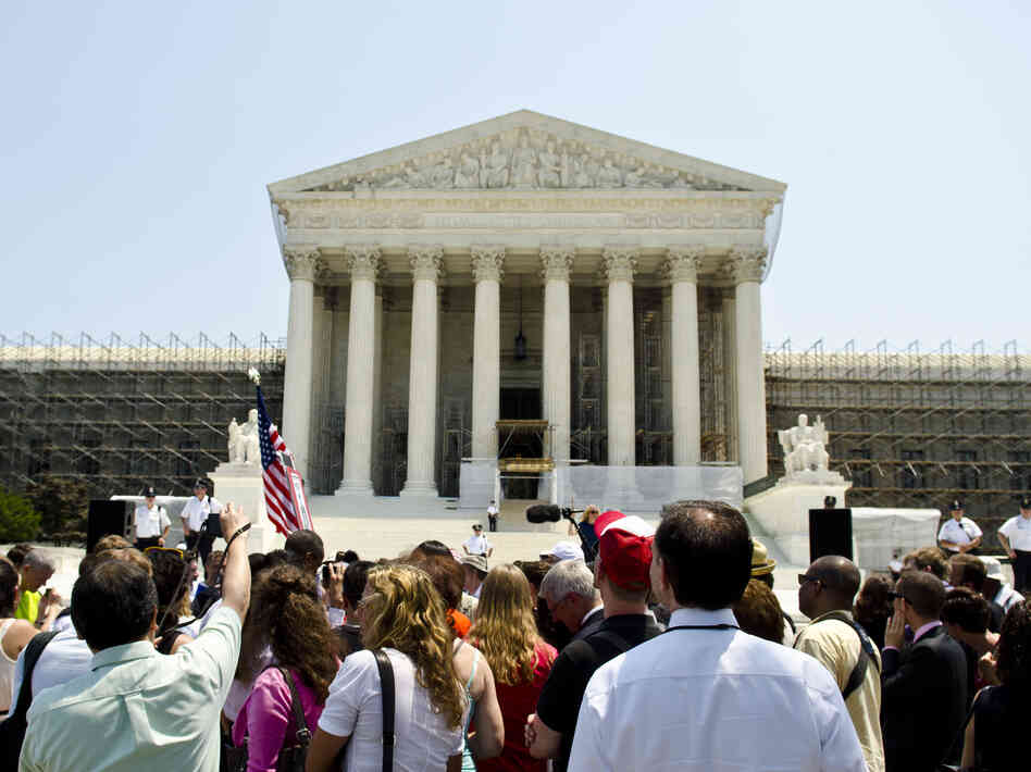 Protesters stand outside the U.S. Supreme Court on Thursday. The court's ruling upholding the federal health care law is expected to have wide-reaching implications for businesses.