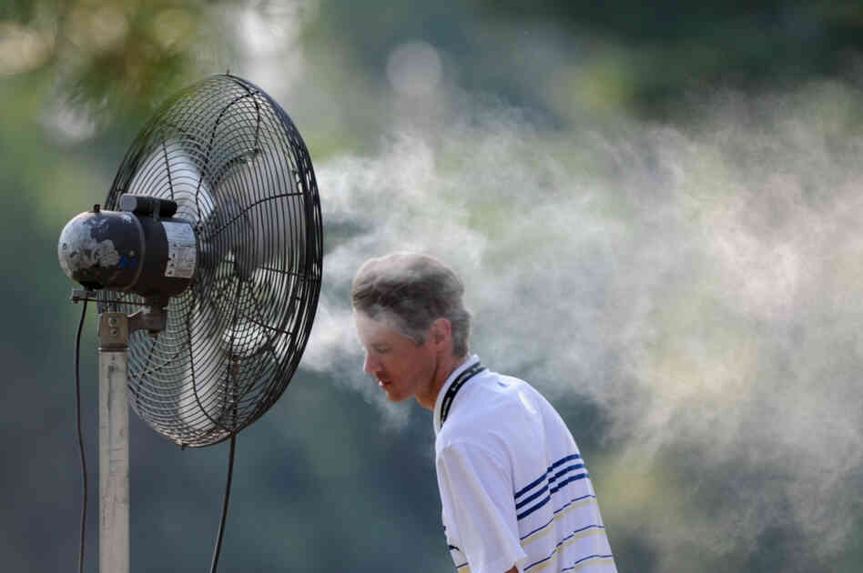 A spectator cools off with a spray mist during first round play Friday at the AT&T National at Congressional Country Club in Bethesda, Md. 
