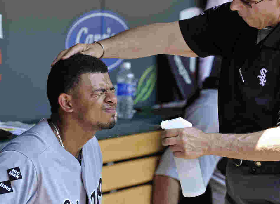 Chicago White Sox' Eduardo Escobar closes his eyes as trainer Herm Schneider sprays him with cool water during a baseball game against the Minnesota Twins in Minneapolis on Wednesday.