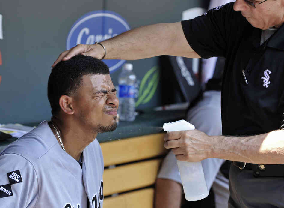 Chicago White Sox' Eduardo Escobar closes his eyes as trainer Herm Schneider sprays him with cool water during a baseball game against the Minnesota Twins in Minneapolis on Wednesday.